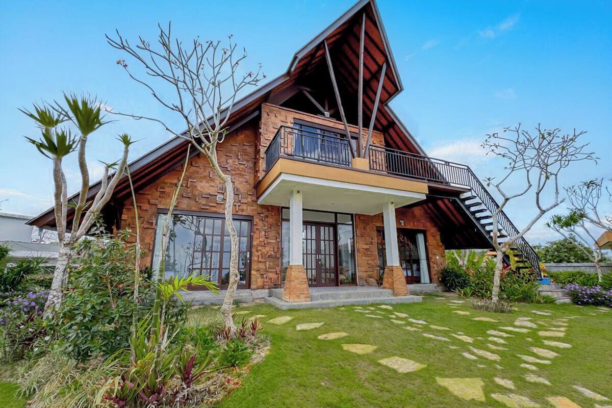 A modern house with a sloped roof, a balcony, and a staircase leading to the upper floor.