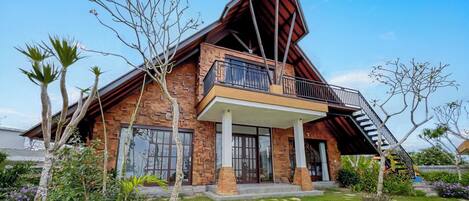 A modern house with a sloped roof, a balcony, and a staircase leading to the upper floor.