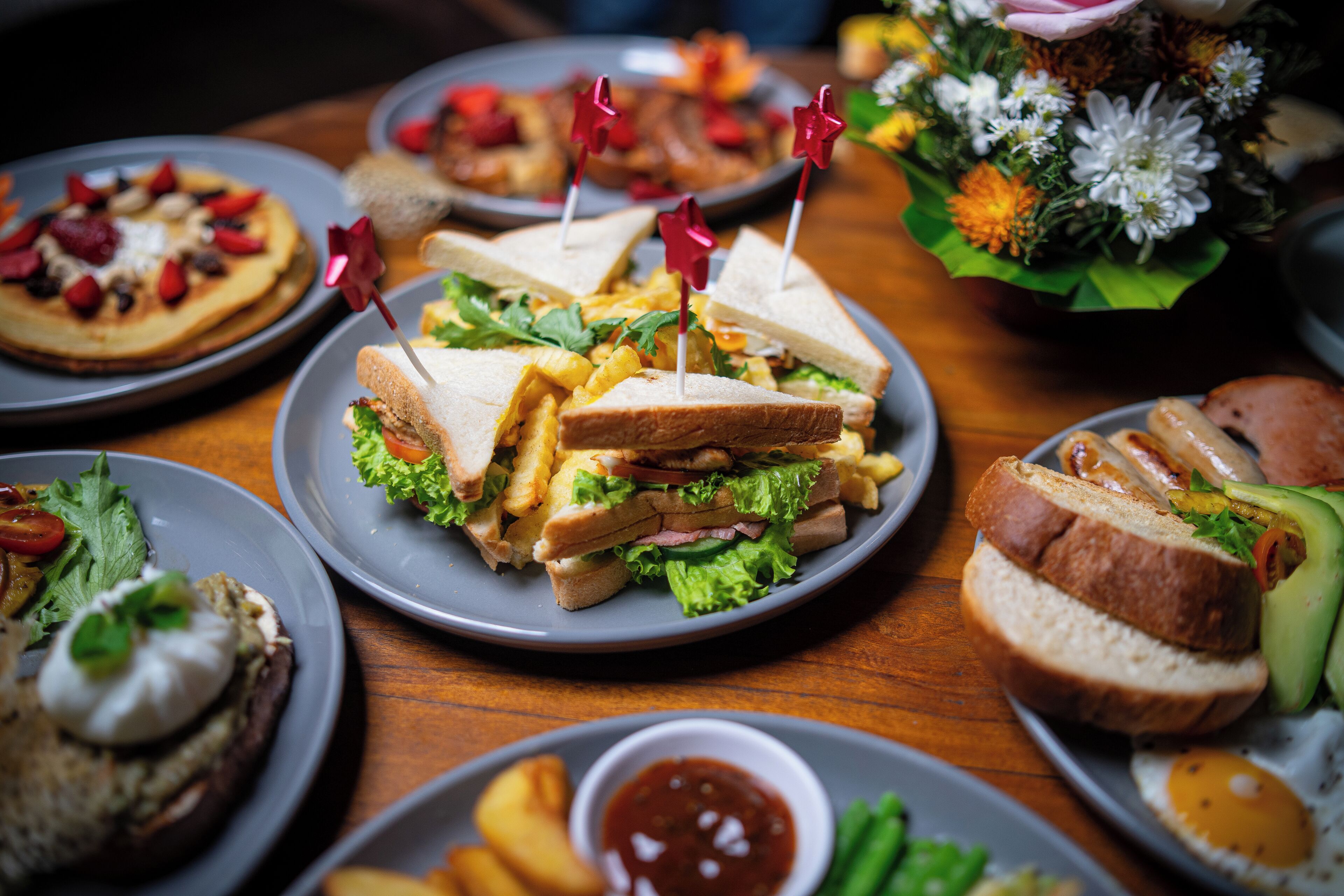 A variety of plated dishes including sandwiches, fries, and a salad.