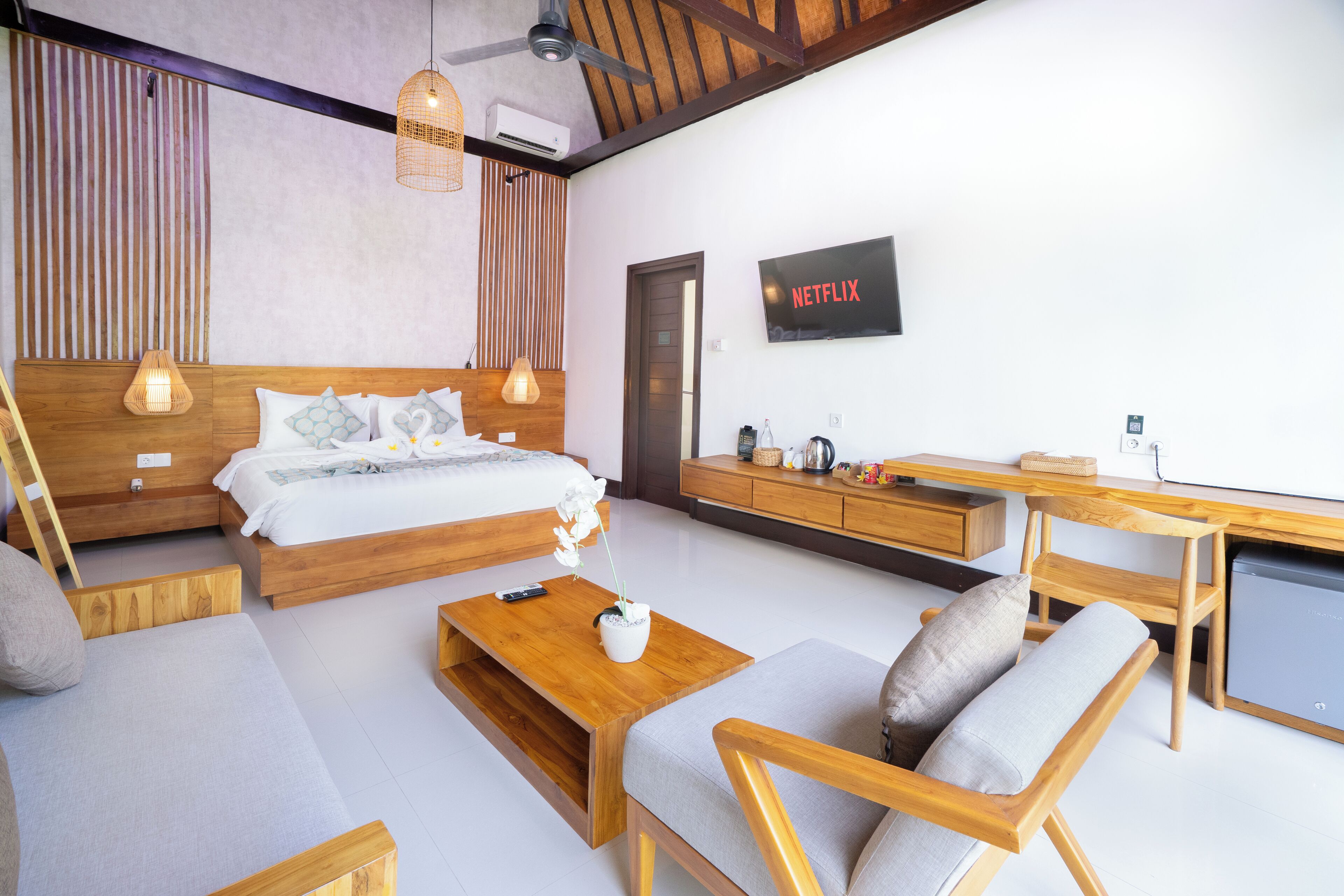 A modern bedroom with a bed, wooden furniture, a desk, and a TV.