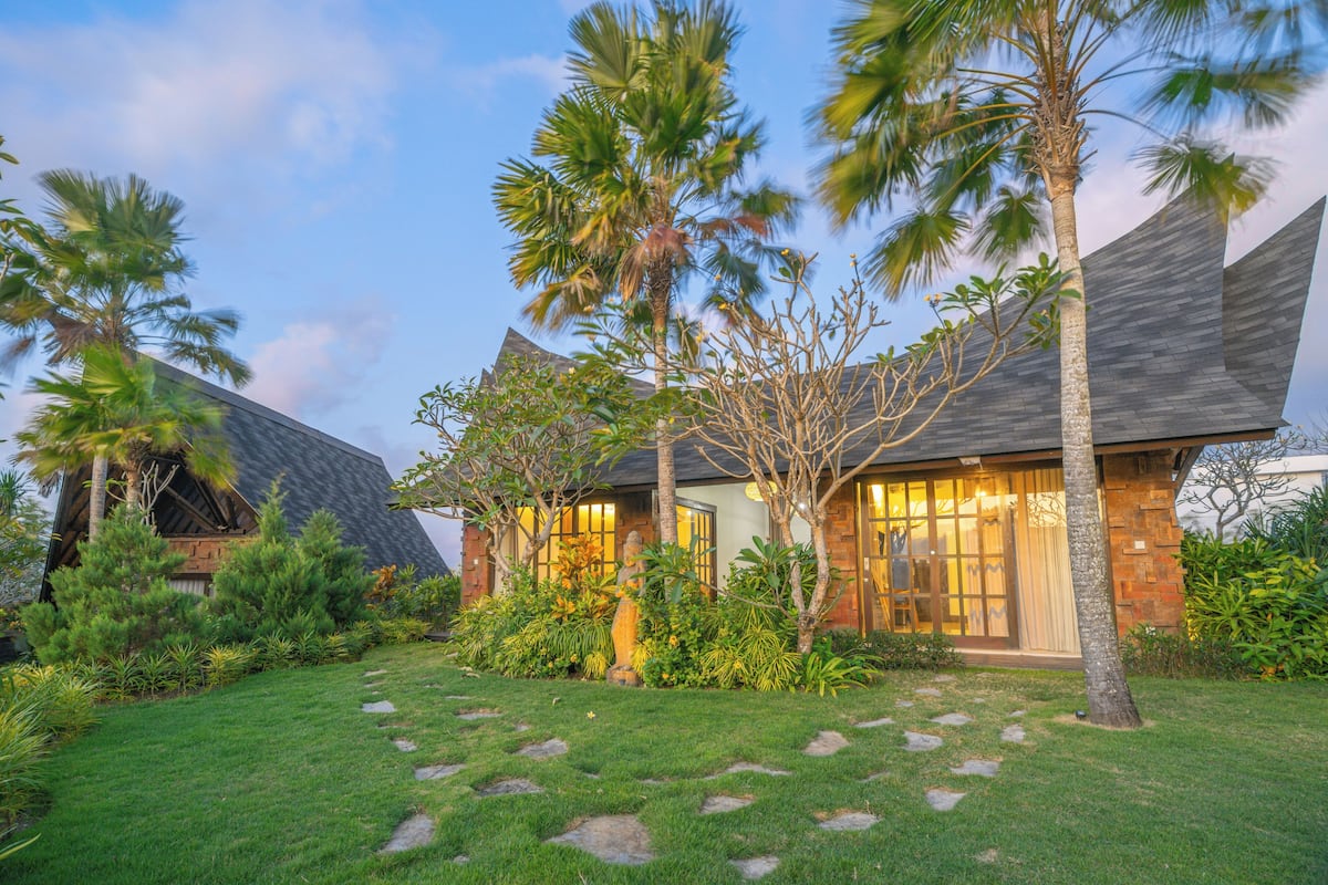 A modern house with a well-maintained lawn and palm trees.