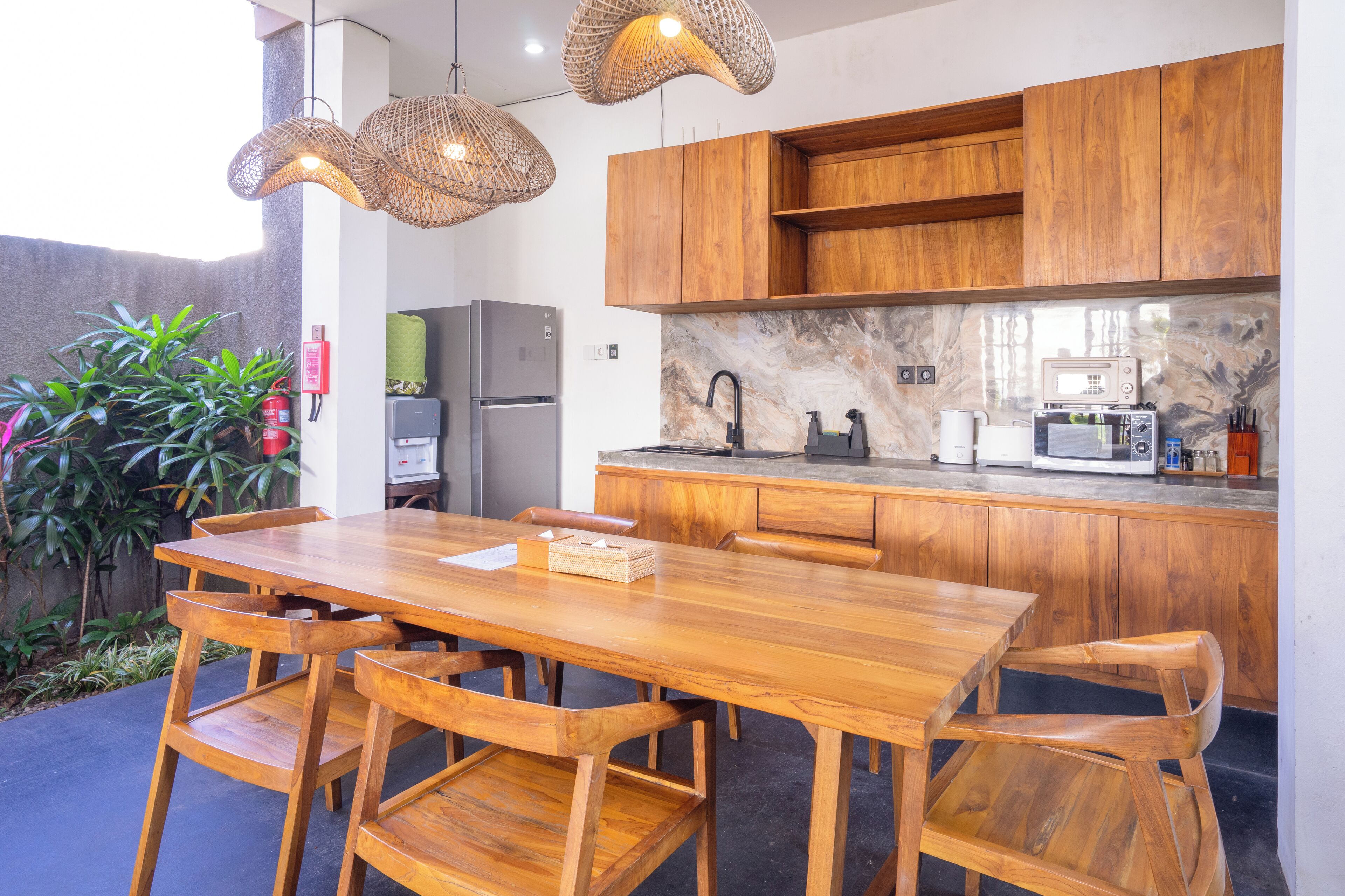 Une cuisine moderne avec des meubles en bois, un pare-feu en marbre et un coin repas comprenant une table et des chaises en bois.