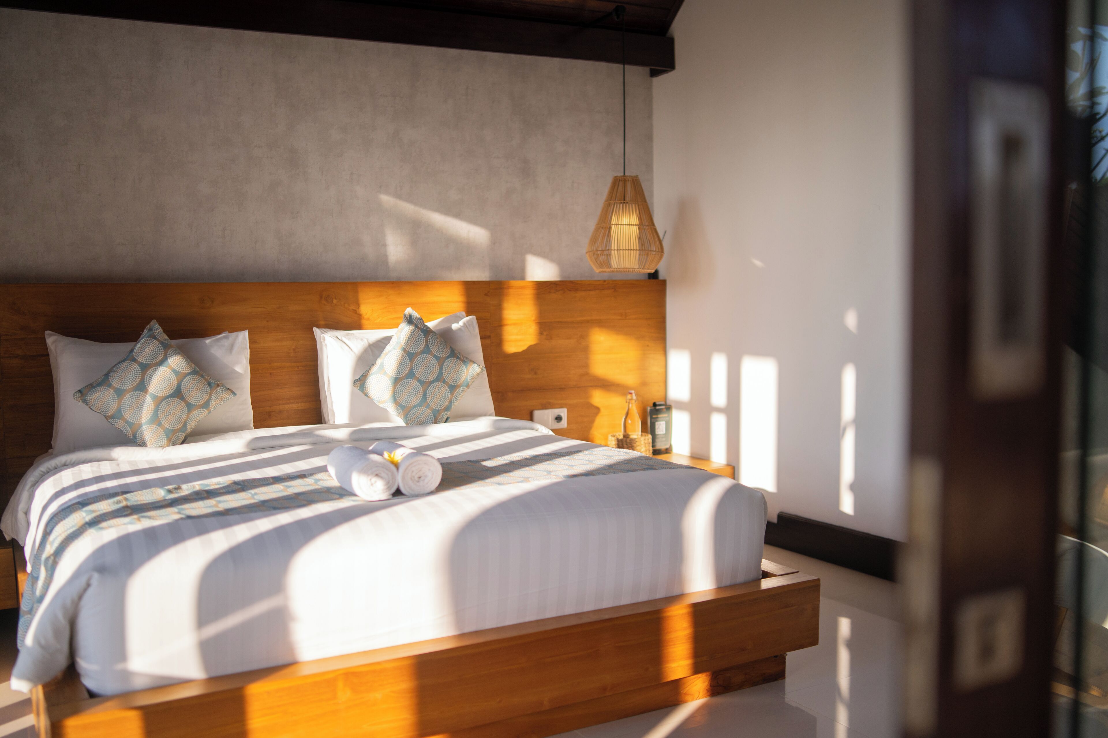Una camera da letto moderna con una testiera in legno, un letto grande con biancheria a righe e un comodino con una lampada.