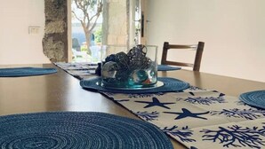Una mesa de comedor con un centro de cristal, individuales azules y un camino de mesa estampado.