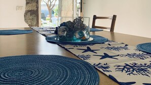 Un comedor con mesa de madera, individuales azules y un centro de mesa de cristal.