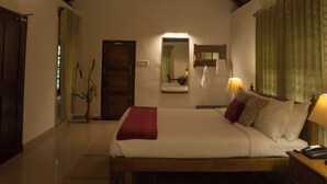 A bedroom with a wooden ceiling, a bed with pillows, a nightstand, a mirror, and a door.