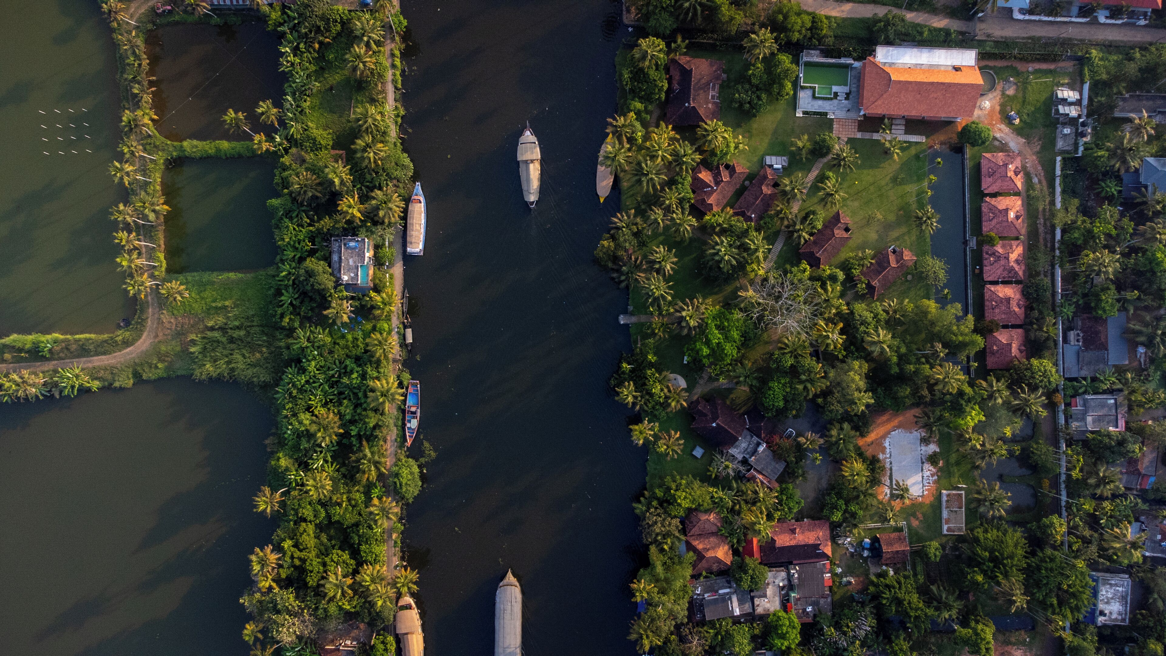 Vue aérienne d’une zone riveraine avec des bateaux, un petit quai et des immeubles résidentiels aux toits rouges.