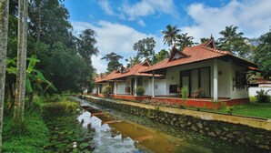 A traditional building with a tiled roof, a waterway with lily pads, and lush greenery.