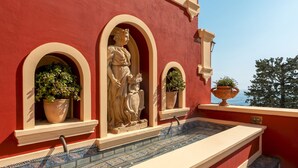 A red building with a tiled pool, statues, and potted plants. - Palazzo San Pietro by Elite Villas (Positano)