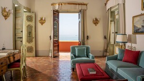A room with a view of the sea, a sofa, a chair, a desk, and a cabinet. - Palazzo San Pietro by Elite Villas (Positano)
