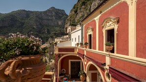 A building with a red facade, arched windows, and potted plants. - Palazzo San Pietro by Elite Villas (Positano)