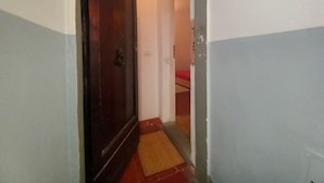 Un pasillo estrecho con una puerta de madera y un felpudo rojo en la entrada.