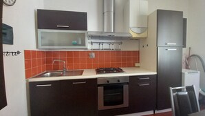 Una cocina compacta con armarios oscuros, una estufa de acero inoxidable y un microondas.