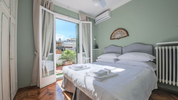 A bedroom with a bed, a radiator, a window with curtains, and a view of the outside. - Maggio 54 in Florence (Florence)
