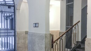 A staircase with a metal railing leading to an upper floor, flanked by white walls and stone flooring. - Maggio 54 in Florence (Florence)
