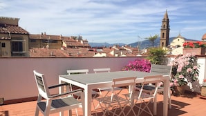 A terrace with a table and chairs, overlooking a town with buildings and a church tower. - Maggio 54 in Florence (Florence)