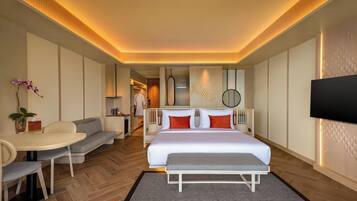 Una habitación de hotel moderna con una cama grande, un área de descanso con una mesa y un televisor en la pared.
