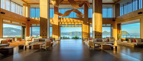 Un vestíbulo espacioso con vista al mar, techo de madera y muebles modernos.