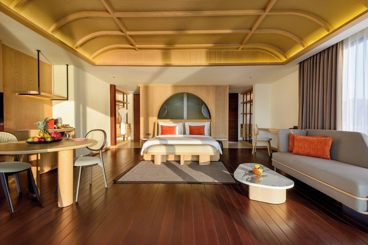 Ein geräumiges Schlafzimmer mit einem großen Bett, einem Schlafsofa, einem Esstisch mit Stühlen und einem kleinen Couchtisch.