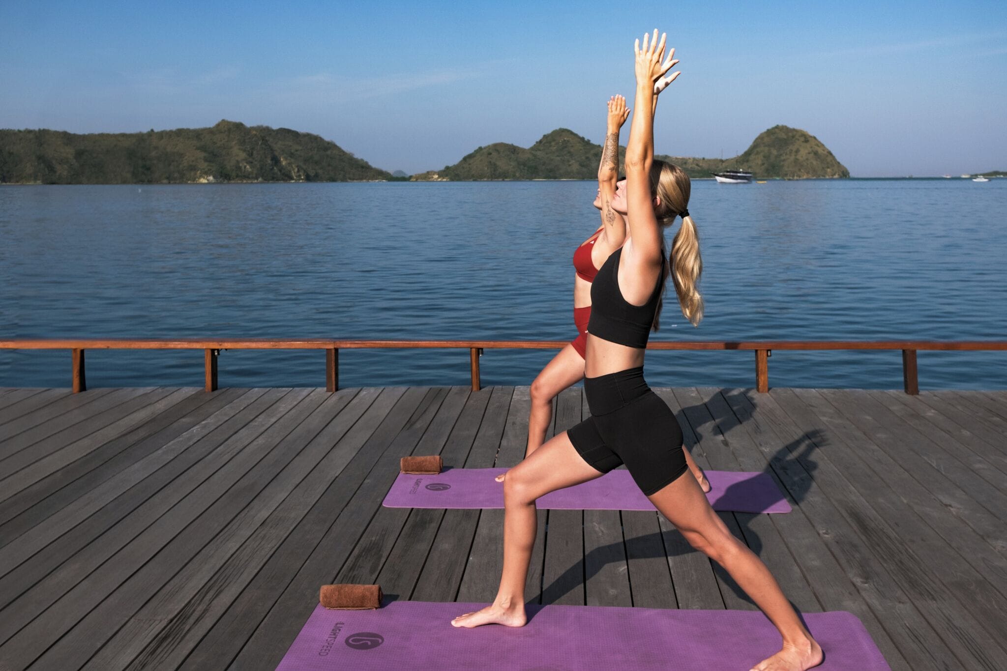 A wooden deck with yoga mats and a person performing a yoga pose.