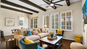 A living room with a sofa, armchairs, a coffee table, and a ceiling fan. - Hidden Palms A | 1BR Legacy Villa (La Quinta)