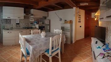 Una cocina compacta con armarios blancos, una mesa de comedor con sillas, un televisor y un letrero que dice 'Welcome'.