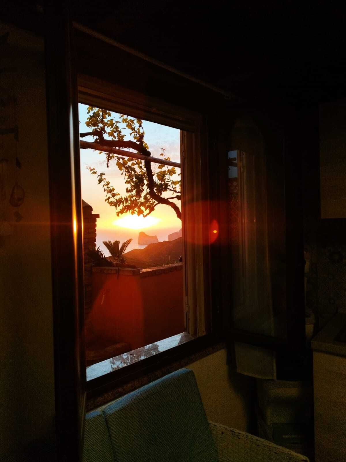 Una habitación con ventanal a un atardecer, una silla y una mesita.