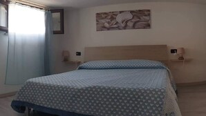 A bedroom with a bed, a nightstand, a wall-mounted lamp, and a floral wall decoration. - Vista Sul Pandi Zucchero -HolidayHouse- (Iglesias)