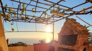 An outdoor patio with a brick oven, a table with a patterned tablecloth, and a pergola with climbing plants. - Vista Sul Pandi Zucchero -HolidayHouse- (Iglesias)