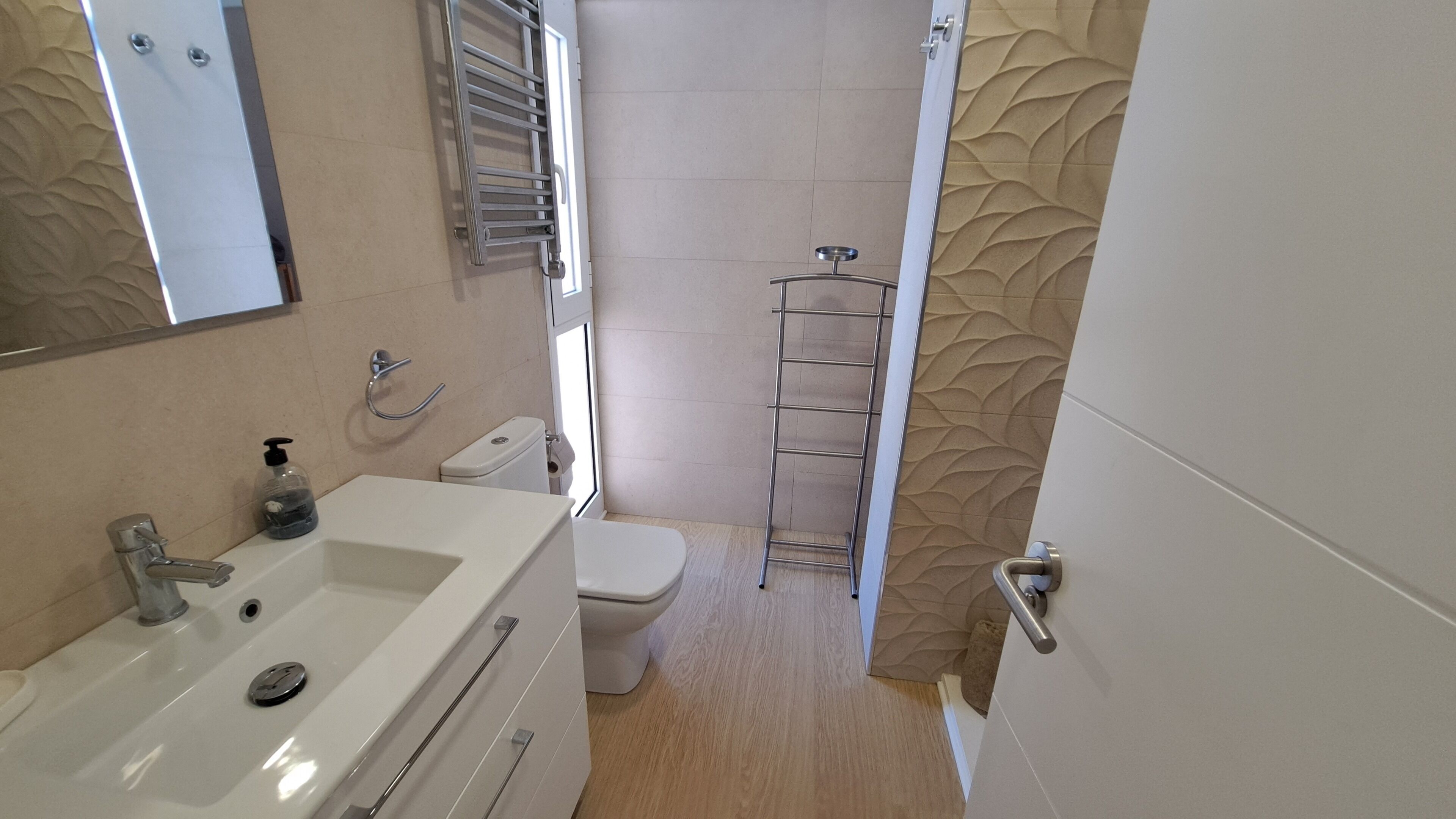 Une salle de bain avec un lavabo blanc, des toilettes et un porte-serviettes.