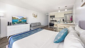 Een moderne hotelkamer met een groot bed, een bank, een eethoek en een keuken.