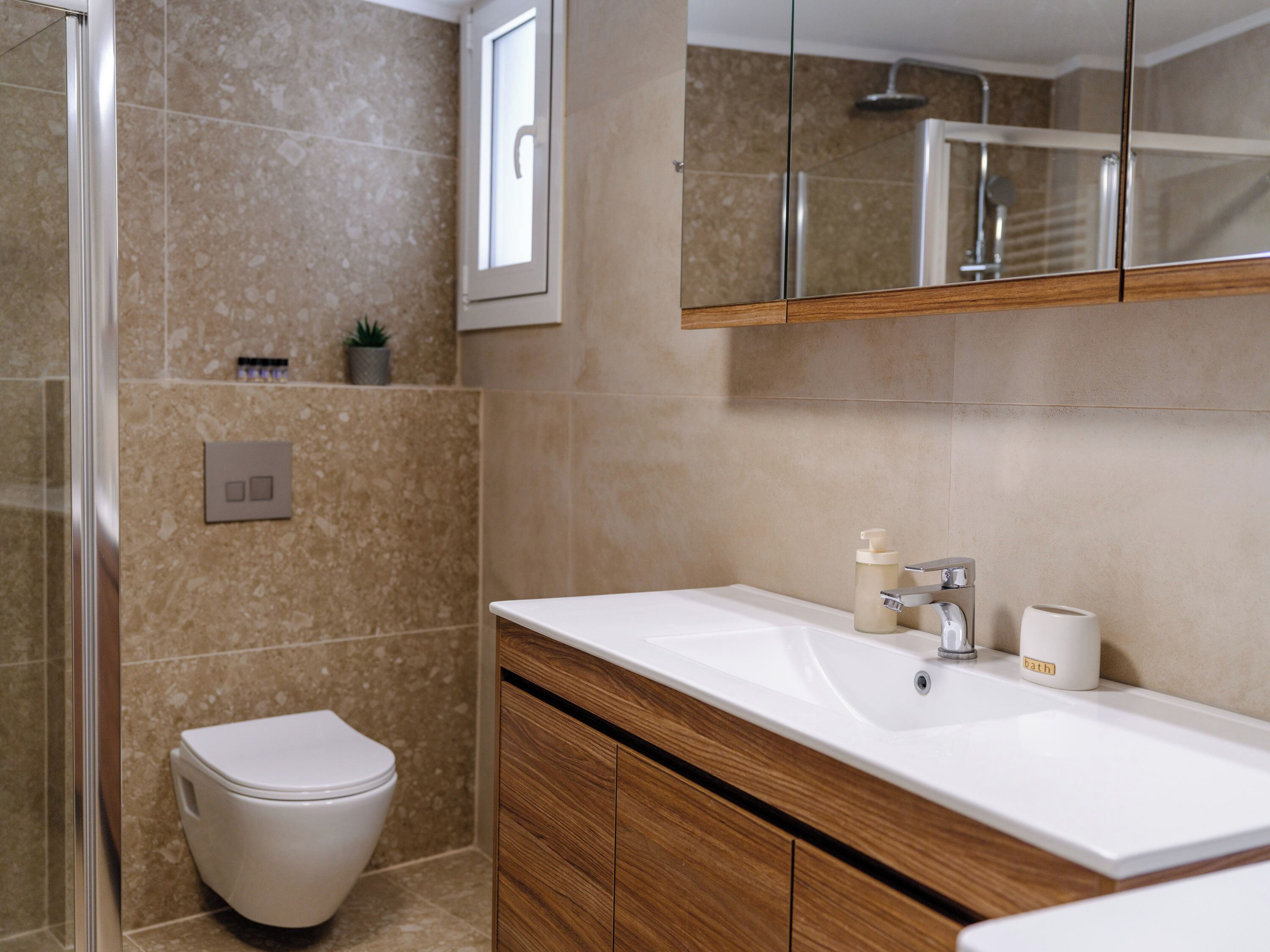 Une salle de bain moderne avec un lavabo blanc, un meuble-lavabo en bois et une cabine de douche en verre.