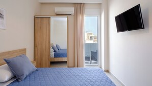 Een hotelkamer met een bed, een aan de muur bevestigde televisie en een schuifdeur naar een balkon.