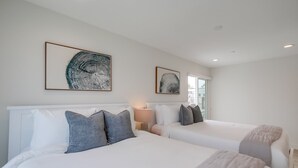 Habitación de hotel con dos camas, un ventanal grande y obras de arte en las paredes.