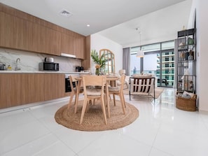 Une cuisine moderne avec des meubles en bois, une table de salle à manger ronde entourée de chaises et une grande fenêtre offrant une vue sur la ville.