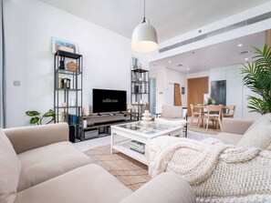A modern living room with a sofa, coffee table, TV, and shelving unit.