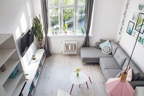Relax in a spacious living room with a large window offering a view of lush greenery, a comfortable sofa, and a stylish coffee table.