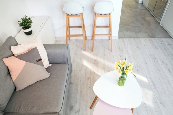 Relax in this serene space with a sofa, table, and chairs, surrounded by a vase with flowers and a potted plant.