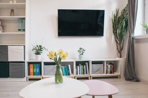 Relax in this stylish living room with a flat-screen TV, round table, and comfortable seating.