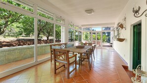 A spacious patio with a wooden table and chairs, large windows, and a view of trees. - 4034 Villa Rodio by Barbarhouse (Ceglie Messapica)