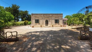 A stone building with a central entrance, surrounded by a paved courtyard and potted plants. - 4034 Villa Rodio by Barbarhouse (Ceglie Messapica)