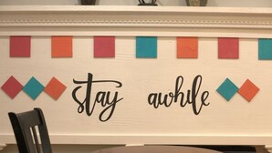 A wall with a decorative sign that reads "stay awful" and colorful geometric shapes above it. - Rest and relaxation in Conyers. (Conyers)