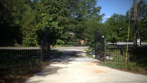 A paved pathway leading through a metal gate into a wooded area. - Rest and relaxation in Conyers. (Conyers)