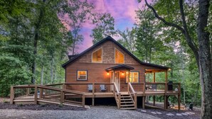 A wooden cabin with a deck, surrounded by trees. - Famtastico - Great Deal! Games, Hot Tub, Pets (Morganton)