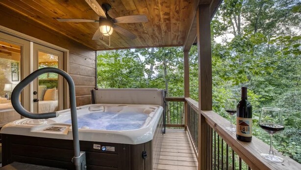 A wooden deck with a hot tub, a glass of wine, and a bottle of wine. - Famtastico - Great Deal! Games, Hot Tub, Pets (Morganton)