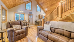 A spacious living area with leather sofas, a dining table, and a staircase. - Famtastico - Great Deal! Games, Hot Tub, Pets (Morganton)