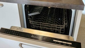 A kitchen with a built-in dishwasher, a stainless steel sink, and a wooden rack. - The Starry Cottage Retreat (Vitrac)