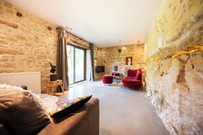 A room with stone walls, a fireplace, a red chair, and a sofa. - The Starry Cottage Retreat (Vitrac)