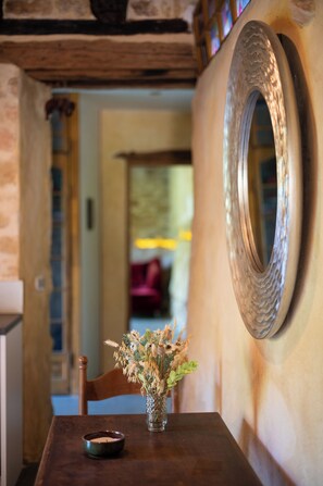 A wooden table with a candle, a vase with dried flowers, and a large mirror on the wall. - The Starry Cottage Retreat (Vitrac)