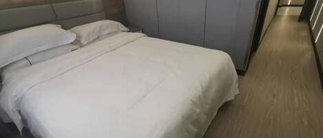 Quarto de hotel com uma cama, um guarda-roupa e piso de madeira.